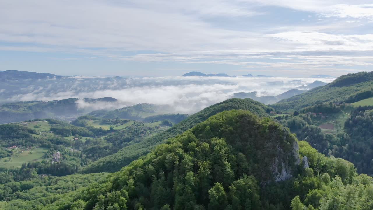 aerial of low clouds over mountains on a beautiful sunny day. Southern Slovenia