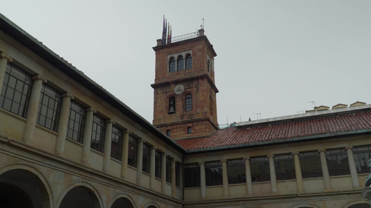 Chiostro maestoso dell'edificio storico dell'Università di Oviedo nelle Asturie, Spagna. Un imponente campanile con orologio si erge sopra gli archi