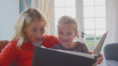 la abuela y la nieta mirando el álbum de fotos en el salón en casa juntos