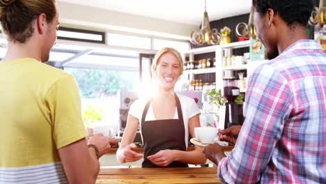 smiling waitress serving cup of coffee to customer