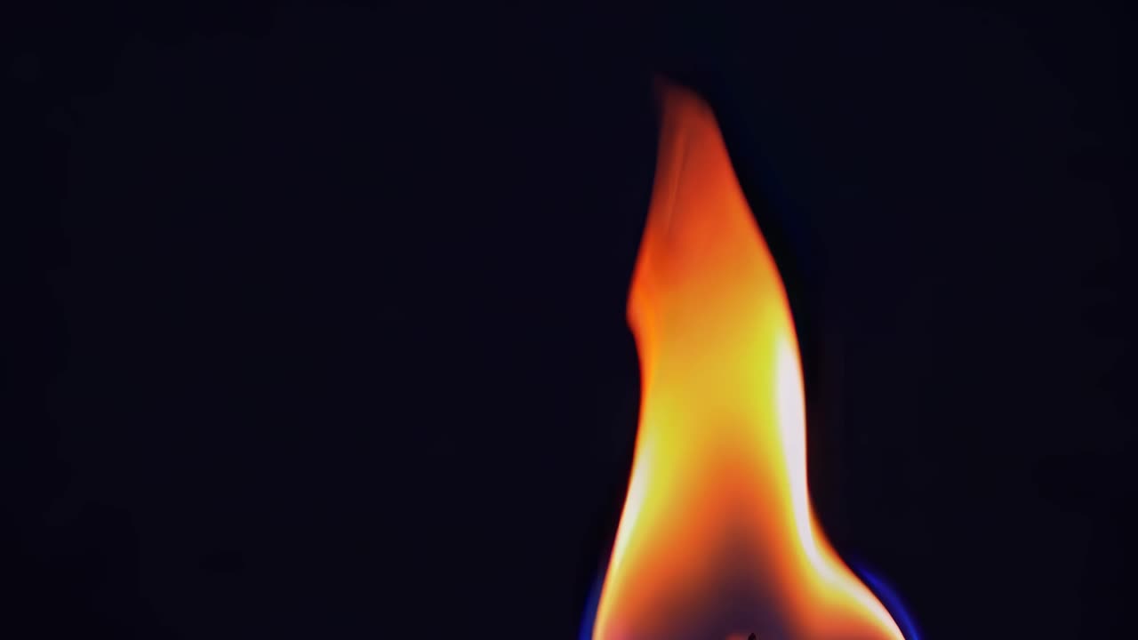 Close-up video of a single flame against a dark background, capturing the fluid motion and vibrant