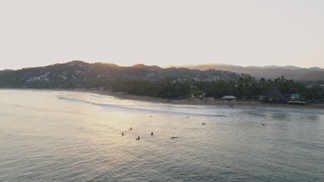 toma aérea de surfistas en el agua que se elevan para revelar el vasto océano detrás, 4k