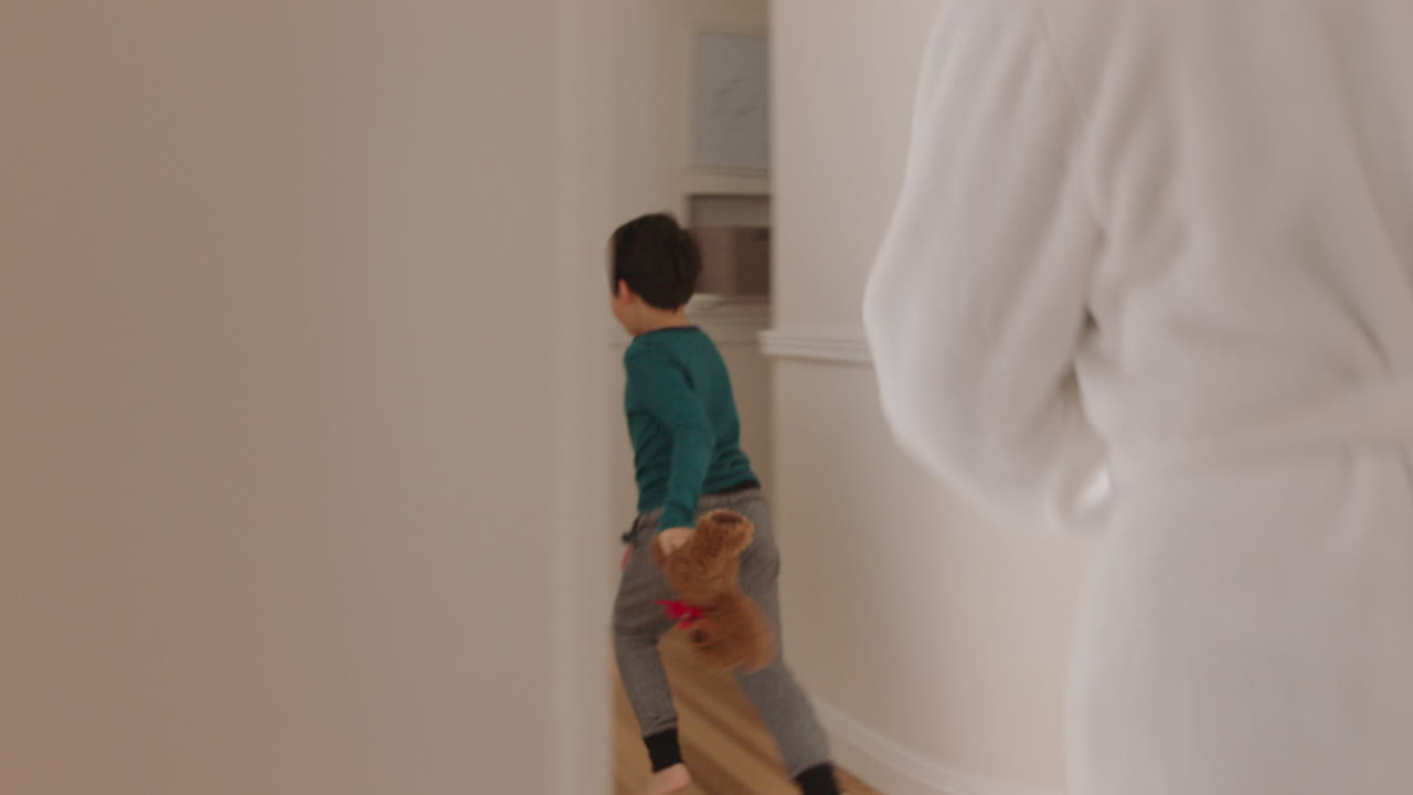 happy asian mother playing catch with little boy running through house mom chasing son enjoying fun weekend together 4k footage