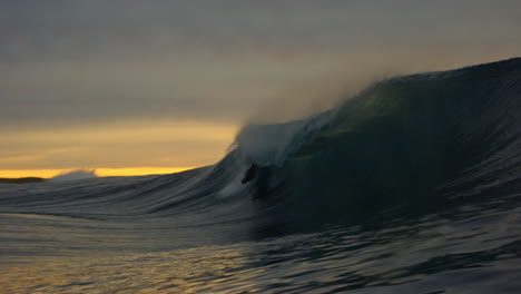 Leuchtendes-Gelbes-Licht,-Während-Der-Surfer-Bei-Sonnenuntergang-In-Zeitlupe-über-Die-Wasserfälle-Fährt