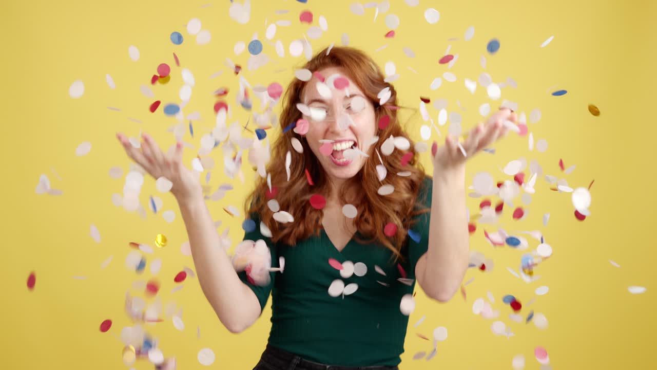 Joyful woman celebrating with confetti on a yellow background