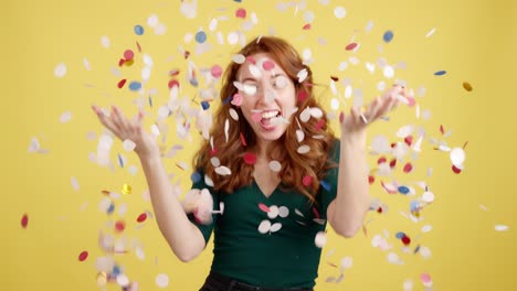 joyful woman celebrating with confetti on a yellow background