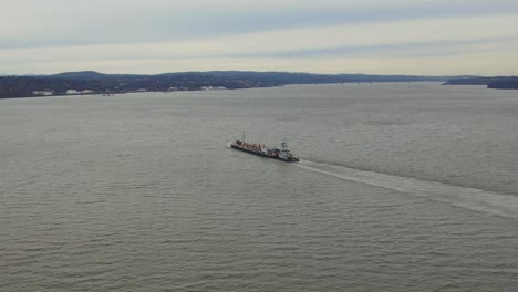 Aerial-footage-following-a-cargo-ship-over-a-large-body-of-water