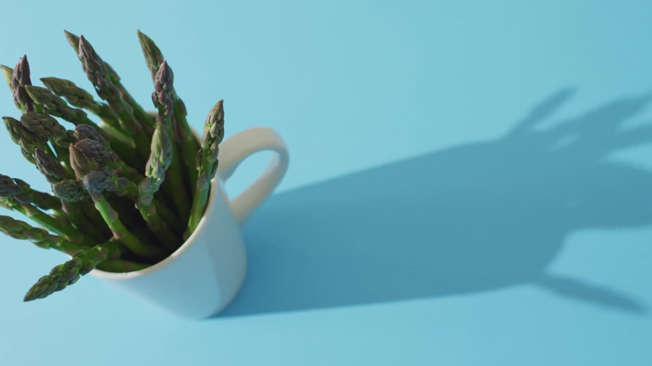 video de espárragos frescos en taza blanca con espacio de copia sobre fondo azul
