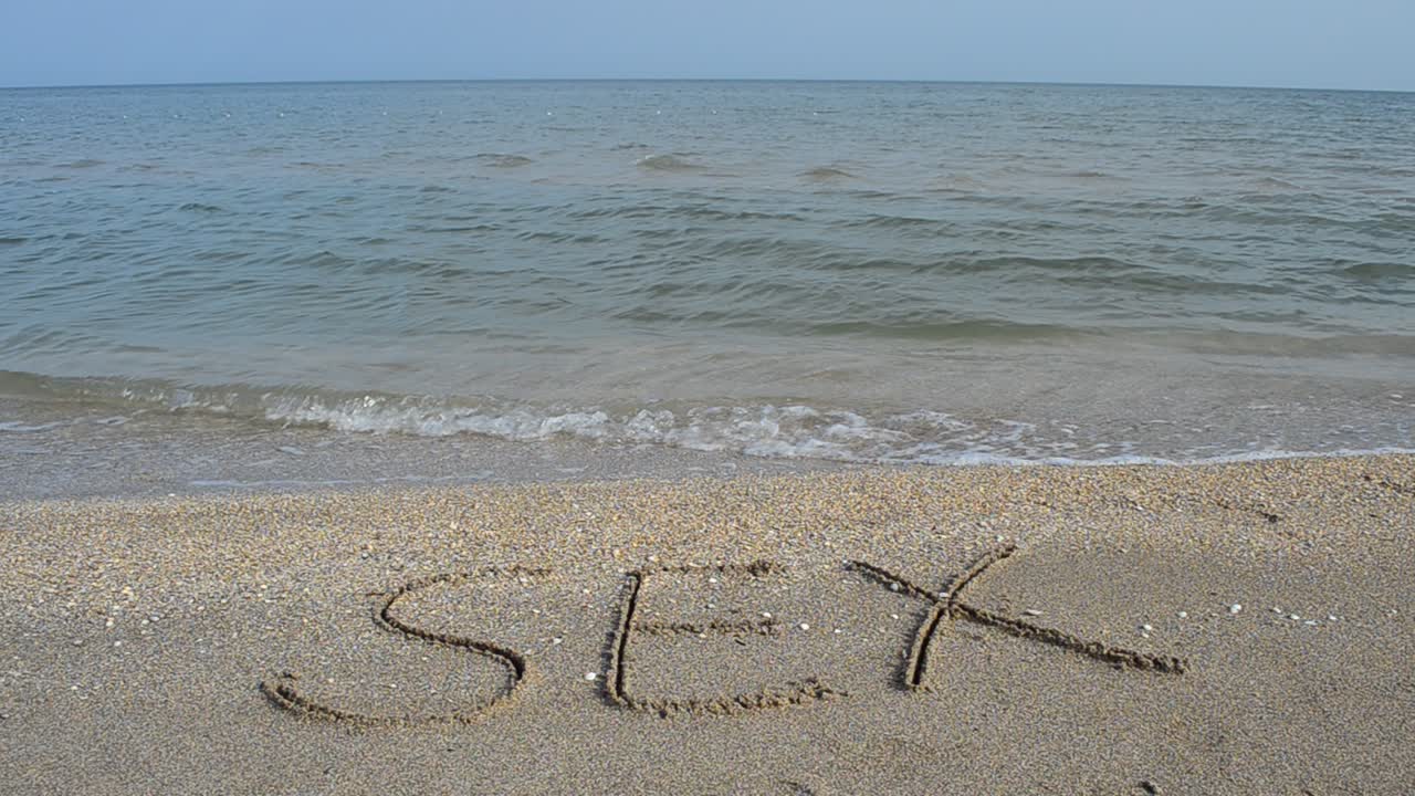 sex handwritten in sand on a beach. Shooting on the beach