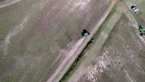 drone footage of soy bean harvesting on a farm field with a harvester or tractor, rotating downward angle aerial shot