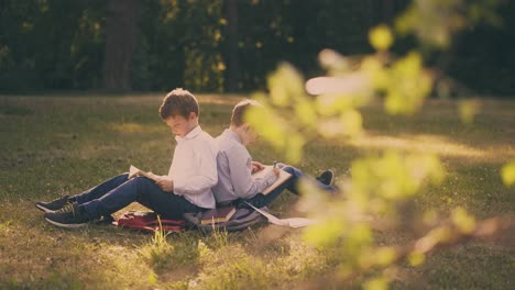 schoolmates-sit-back-to-back-preparing-for-exams-in-garden