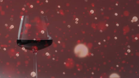 Composite-of-glass-of-red-wine-over-spots-of-light-on-red-background