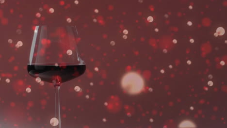 compuesto de un vaso de vino tinto sobre manchas de luz sobre un fondo rojo