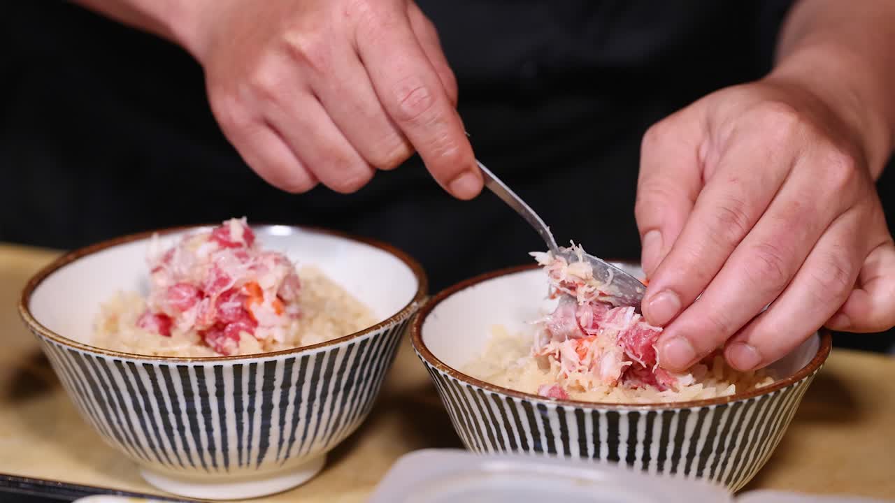 Primo piano di uno chef che sistema con cura polpa di granchio fresco su ciotole di riso a Bangkok