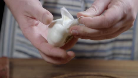 peeling process of head of garlic by chef who is preparing chimichurri sauce