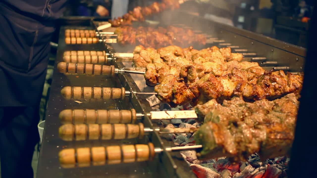 Grilled meat on skewers. Street food. Meat rotating on skewer