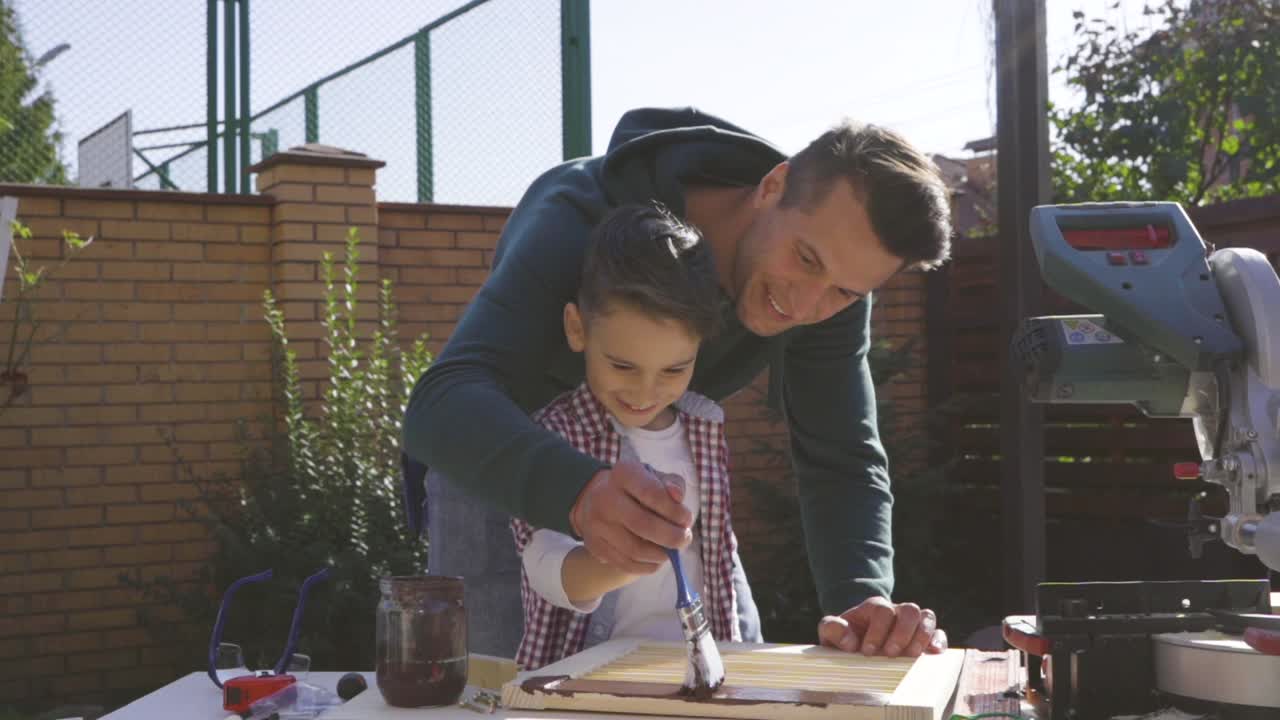el padre y el hijo pintan carpintería juntos. cámara lenta