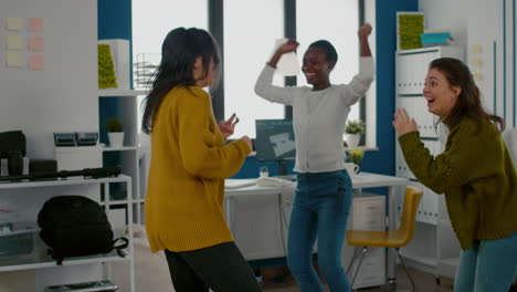 mixed raced happy women dancing cheerfully in startup creative agency office,