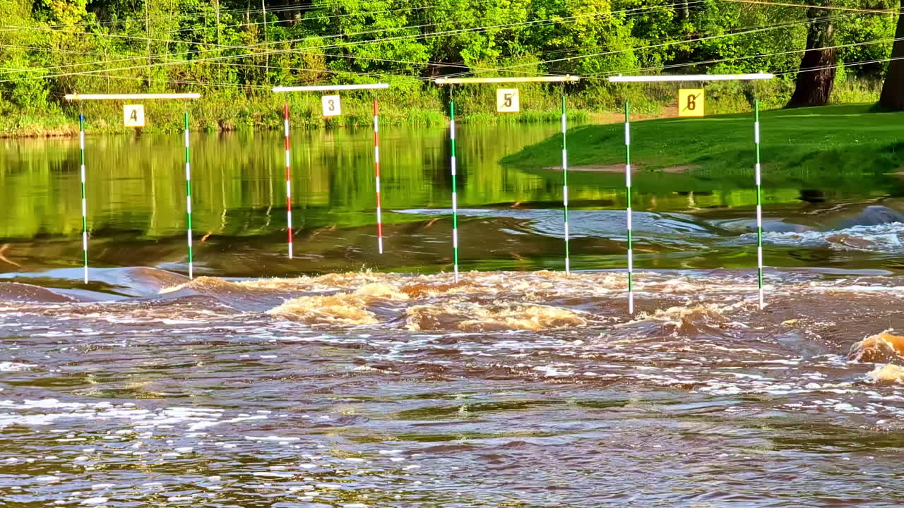 Kayaking slalom gates over rapid water section in outdoor whitewater training course, Gauja river in Valmiera, Latvia