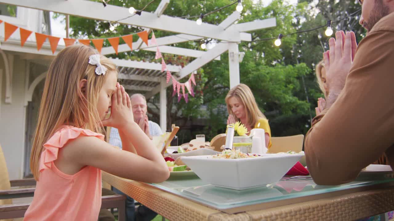 3 세대 가족 이 야외 에서 점심 을 먹기 전 에 기도 하고 있다