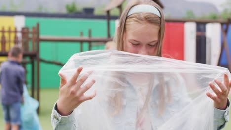 Portrait-of-happy-caucasian-schoolchildren-cleaning-with-bags-at-school-playground