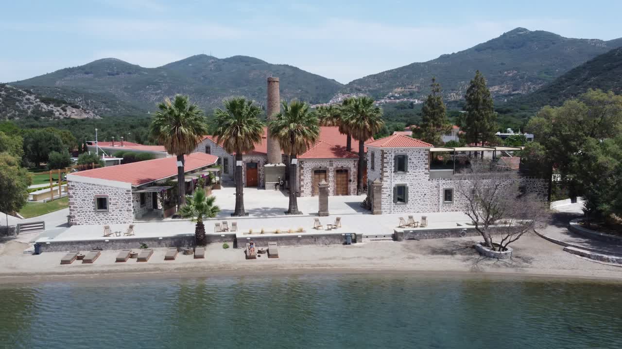 Female tourist reading a book sitting on outdoor lounging chair at a beachfront hotel property, Zaira Hotel, Mytilene, Lesvos Island, Drone shot