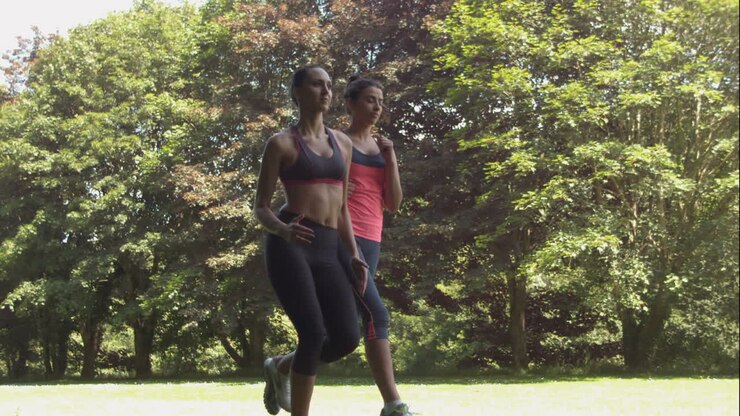 Two friends jogging together in the park on sunny day