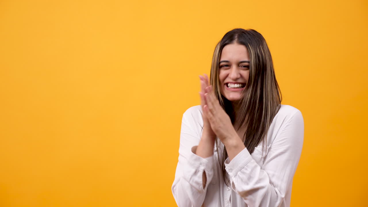 Happy woman clapping hands on yellow background