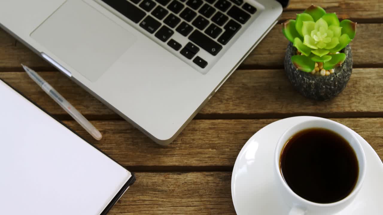 Laptop, pot plant, pen, coffee and notepad on table 4k