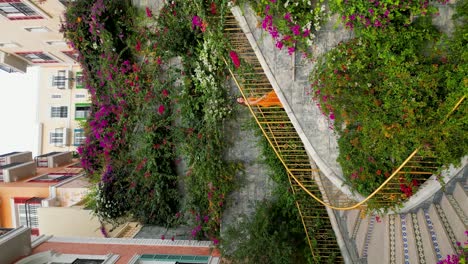 vertical - girl in dress climbing in thang rong stairs decorated with colorful flowers in phu quoc, vietnam. drone shot