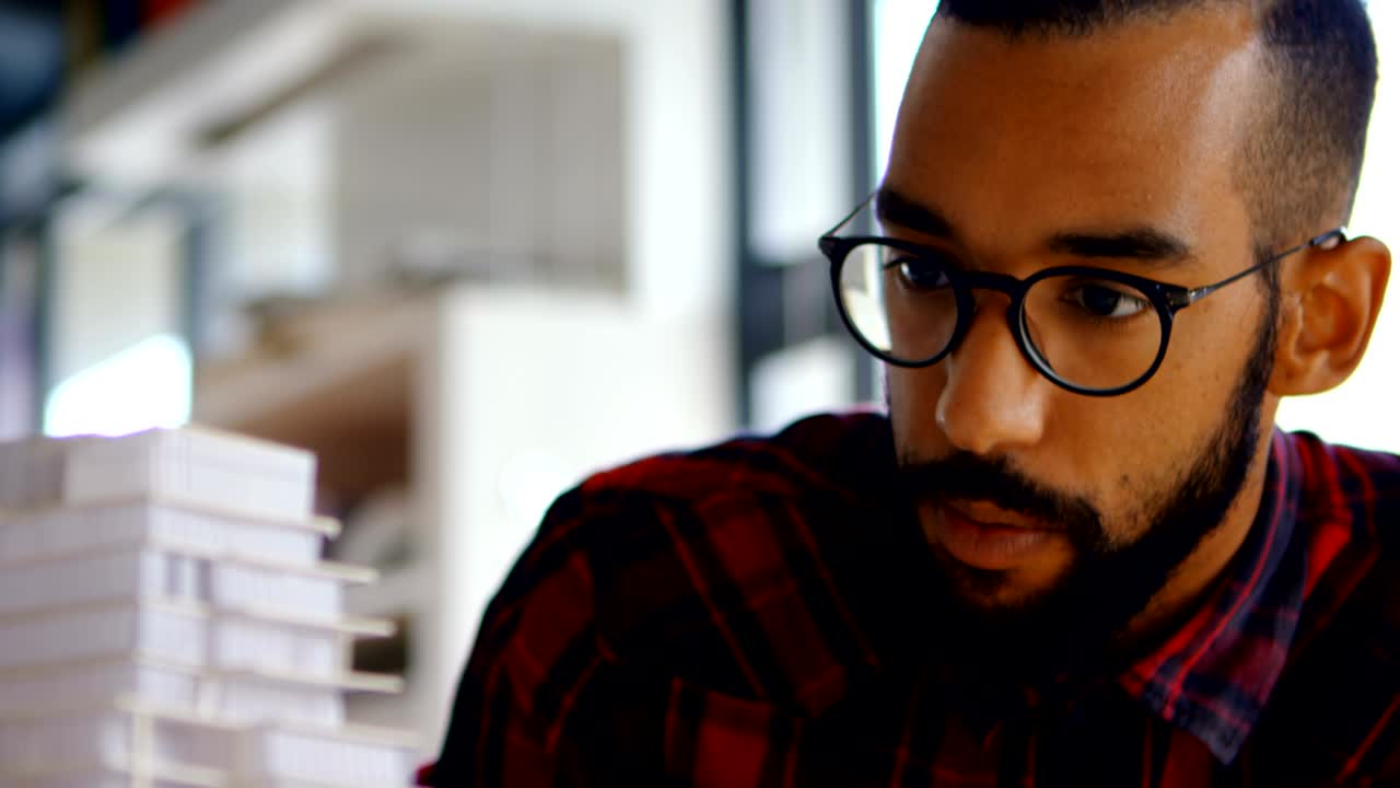 Male architect looking at building model 4k