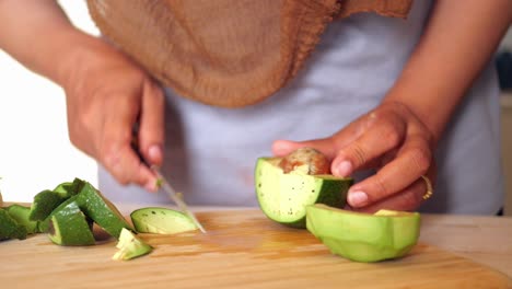 woman cutting avocado on cutting board