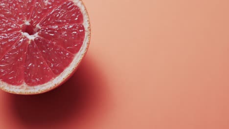 video of sliced red grapefruit with copy space over orange background