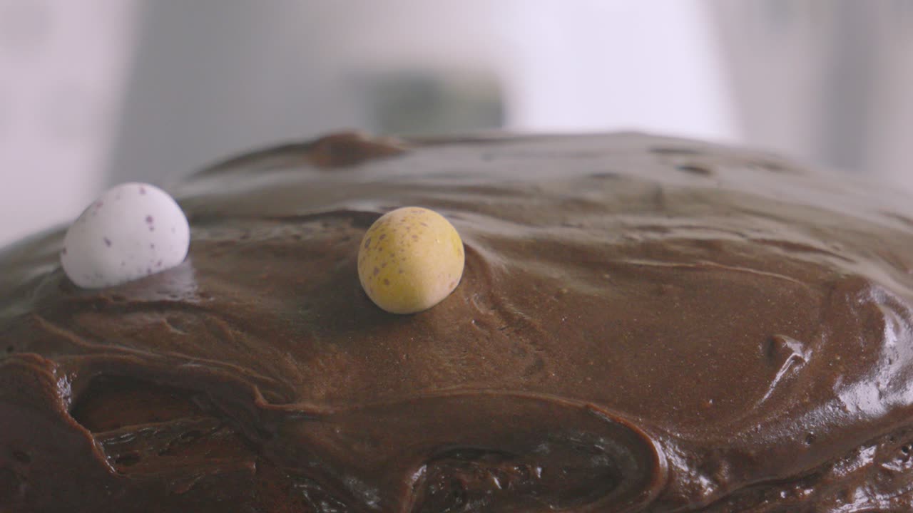 Female Hand Carefully Placing Chocolate Eggs on Cake Ready to Eat at Easter with Creamy Icing Frosting on Top. Slow Motion Baking Food Footage.