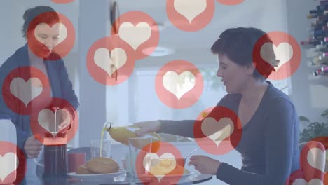 Animation-of-heart-emojis-and-numbers-over-happy-caucasian-female-couple-in-love-at-home