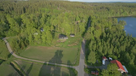 Long-shadows-from-tall-forest-on-edge-of-lake-hide-quaint-vacation-homes-in-scenic-Illerasasjon-Lake,-Sweden