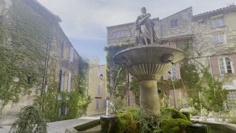 Schöner-Kleiner-Steinbrunnen-Romantisch-Mit-Alter-Figur-Frau-Mit-Wasser-Bei-Schönem-Wetter-Stimmungsvoll