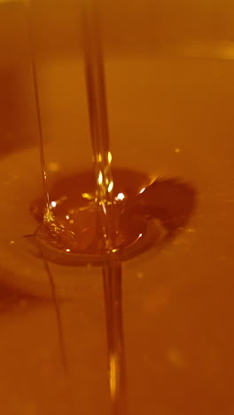 golden liquid freshly gathered honey in a bowl. little streams filling the dish. healthy organic natural food concept close up. vertical video