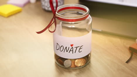 Donate-jar,-table-and-charity-coins-with-change