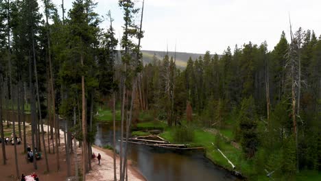 slow downward aerial tilt above a large river and picnic area among the trees near yellowstone in wyoming