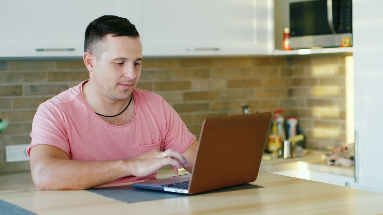 Young Attractive Man Working With Laptop At The Kitchen
