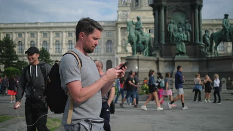 man using smartphone in front of a monument in vienna