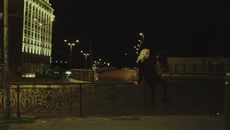 Girl-enjoying-city-view-cars-passing-at-late-night-street-in-urban-area.