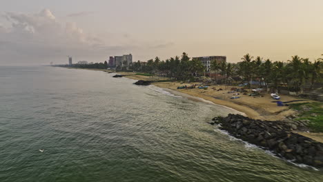 Negombo-Sri-Lanka-Aéreo-V4-Sobrevuelo-Bajo-Con-Drones-A-Lo-Largo-De-La-Costa-De-La-Playa-De-Wellaweediya-Capturando-Casas-Frente-Al-Mar,-Aguas-Tranquilas,-Playas-De-Arena-Y-Un-Amanecer-Dorado---Filmado-Con-Cine-Mavic-3---Abril-De-2023