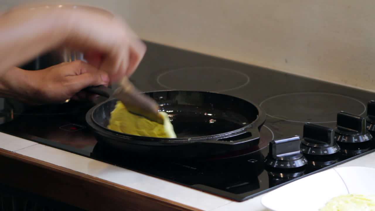 Man cooks and flips food in cast iron skillet