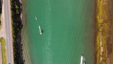 Overhead-aerial-over-Goukou-river-with-pleasure-crafts-speeding-along,-Stilbaai