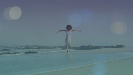 mujer de pie con los brazos extendidos en la playa sobre la animación bokeh ligera