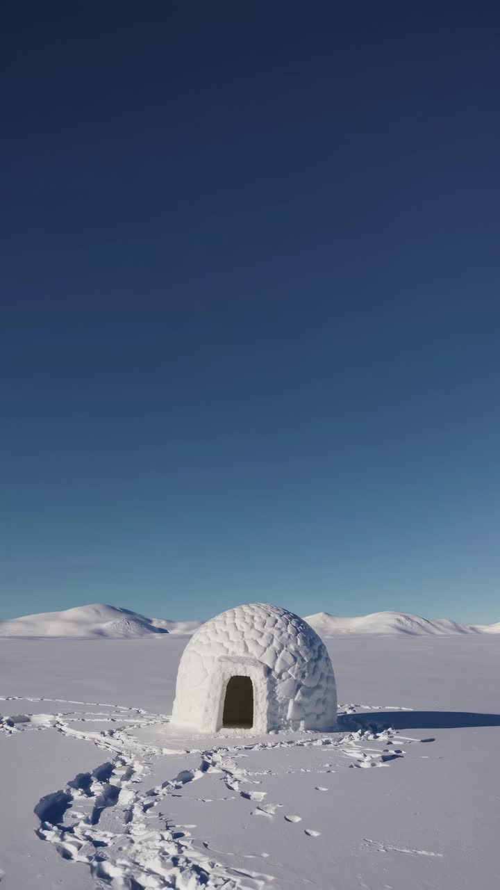 A wide-angle shot of a solitary igloo under a clear blue sky, capturing the serene snowy landscape