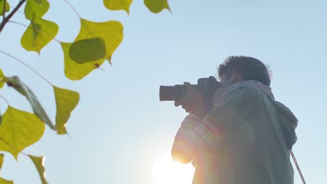 close up side portrait of south asian man taking pictures with dslr, leaves park