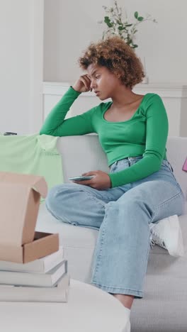 young woman in green top relaxes while scrolling on her phone at home